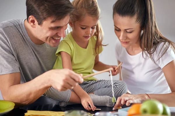 ダイニングルームで遊び心のある雰囲気の中で朝食後に娘と遊んでいる若い両親 一緒に — ストック写真