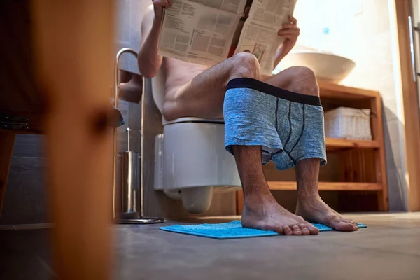 Joven Sentado Inodoro Ambiente Relajado Baño Leyendo Periódico Aseo Necesidad — Foto de Stock