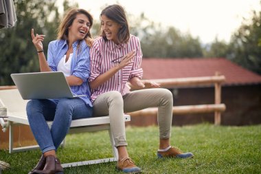 Neşeli bayan arkadaşlar güzel güneşli bir günde bahçede harika vakit geçiriyorlar. Arkadaşlık, birlikte, eğlence.
