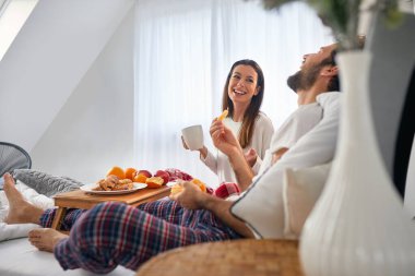 breakfast in bed concept. young couple enjoying in food and coffee in bed, laughing.