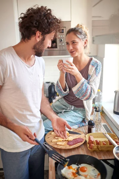 素敵な若い白人カップルが朝食を作ってコーヒーを飲みキッチンで話をして — ストック写真