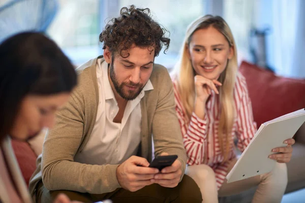一位年轻的商人在和他的女同事在轻松的气氛中通过智能手机发短信 — 图库照片