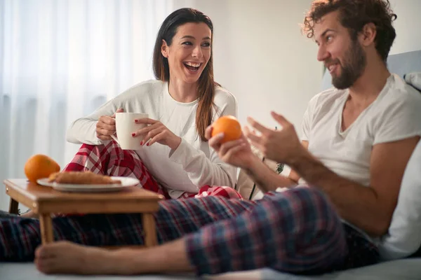 彼らの寝室でベッドで朝食をしながら楽しい時間を過ごしている若いカップル 一緒に — ストック写真