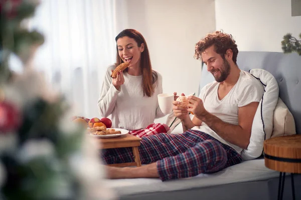 幸せで満足した若い白人カップルは素晴らしいバレンタインの夜の後にベッドで朝食を食べ笑顔でコーヒーを飲みました — ストック写真