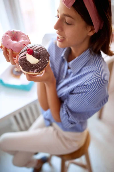 一个年轻迷人的女孩在糕点店的愉快氛围中 对她手中的美味甜甜圈充满了惊奇和渴望 糕点店 — 图库照片