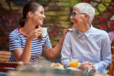 Barda hoş bir ortamda büyükannesiyle kahve içen genç bir kız. Boş zaman, bar, arkadaşlık, açık hava.