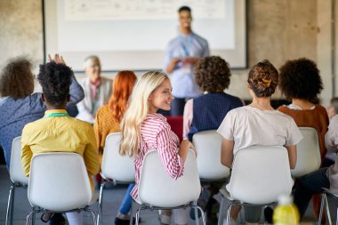 Bir grup yaratıcı genç ofiste keyifli bir atmosferde konferans dinliyorlar.