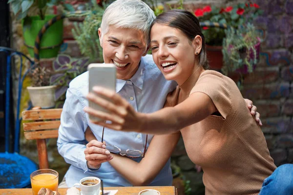 Ung Vuxen Kaukasisk Kvinna Och Äldre Kvinna Ler Tittar Mobiltelefon — Stockfoto