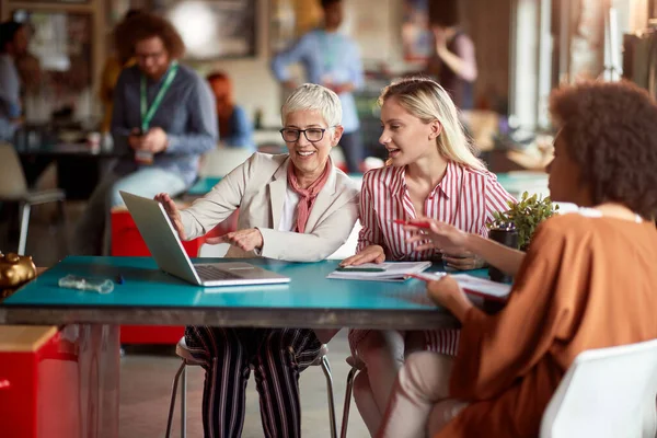 caucasian senior manager showing on laptop business plan to a afro-american female client, together with junior colleague