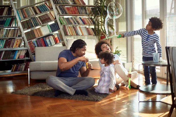 家の明るい雰囲気の中で床で遊んでいる若い幸せな家族と石鹸泡を作ります 一緒に 遊びの時間 — ストック写真