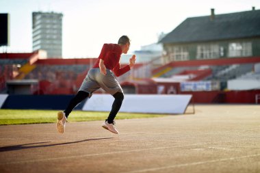 Stadyumda koşan atletik genç adam..