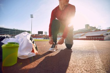 Koşu ayakkabısı bağlayan adam stadyumda antrenman için hazırlan..