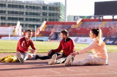 Başlangıç çizgisinde esneyen genç sporcular. Başlangıç çizgisinde gerinen çalıştırıcı. 