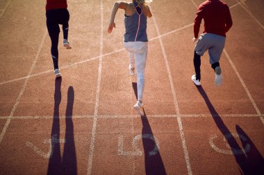 Stadyumda yarış pistinde koşmak için başlangıç pozisyonundaki genç sporcuların arka planı