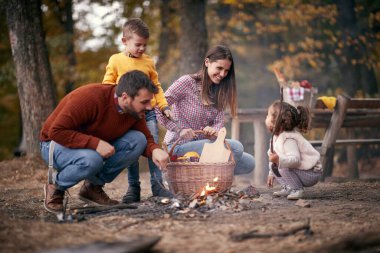 Mutlu aile, güzel bir sonbahar gününde ormanda pikniğe hazırlanıyor.