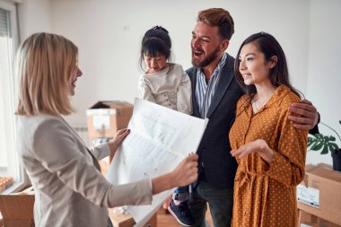 Genç bir aile, hoş bir ortamda bir emlakçıyla satın almak istedikleri ev hakkında konuşuyor. Ev, aile, taşınma.
