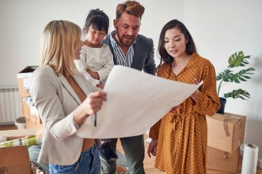 Hoş atmosferdeki bir emlakçı kadın evin planını satın almak isteyen genç bir aileye sunuyor. Ev, aile, taşınma.
