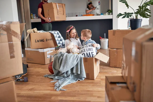 小小的高加索兄弟姐妹 在空纸板箱里玩耍 在新公寓里快乐 他们的父母在后面 新公寓 新公寓 — 图库照片