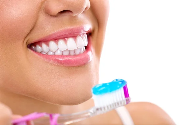 Kvinna med friska tänder håller en tandborste — Stockfoto