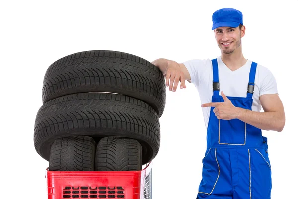 Mecânico alegre apontando em pneus novos — Fotografia de Stock