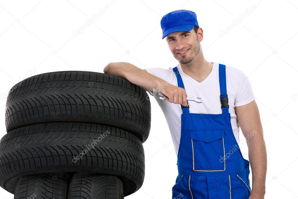 Young mechanic with tires and wrench