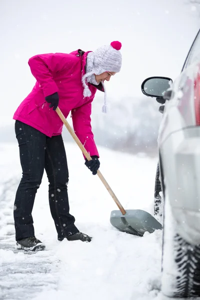 Mulher limpando neve ao redor do carro — Fotografia de Stock