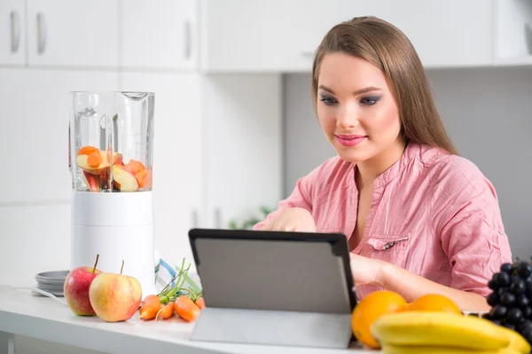Frau in der Küche liest ein Rezept von einem digitalen Tablet — Stockfoto