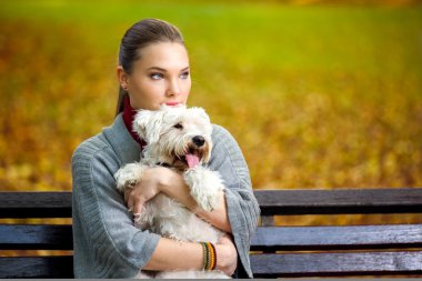 Genç kız köpeğini kucaklıyor.