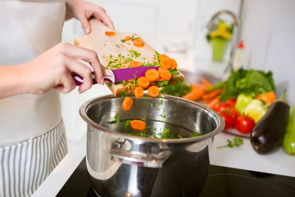 Verduras en la tabla de cortar están cayendo en la olla —  Fotos de Stock