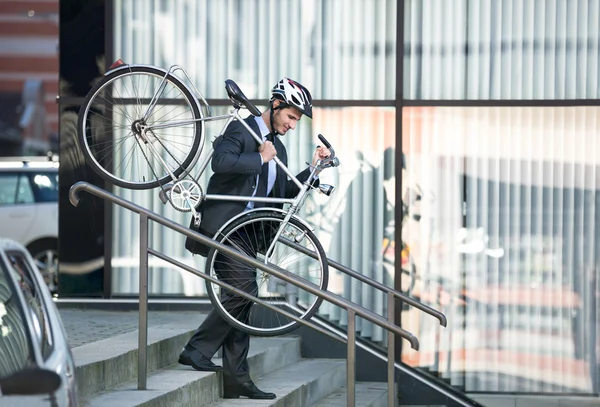 Homme d'affaires portant son vélo — Photo