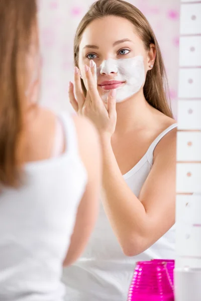 Menina bonito novo colocando máscara facial em seu rosto — Fotografia de Stock