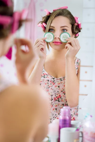 Jovem mulher em roupão de banho com pepino nos olhos — Fotografia de Stock