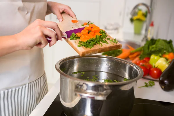 Cutting vegetables on the wooden  board are falling in the pot — Stock Photo, Image