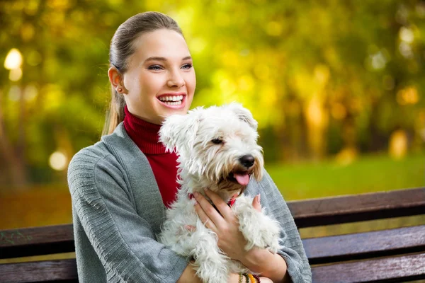 Genç kız köpeğini kucaklıyor.