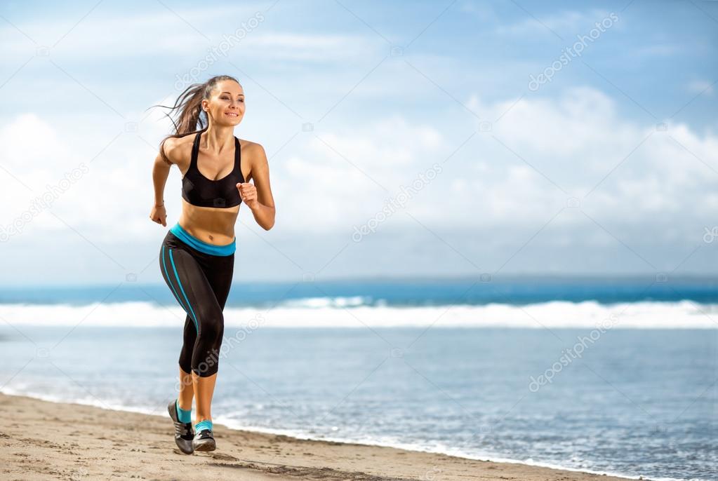 Jogging athlete woman running at sunny beach