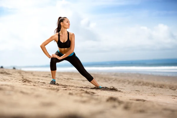 Fit mulher fazendo exercícios para pernas na praia — Fotografia de Stock