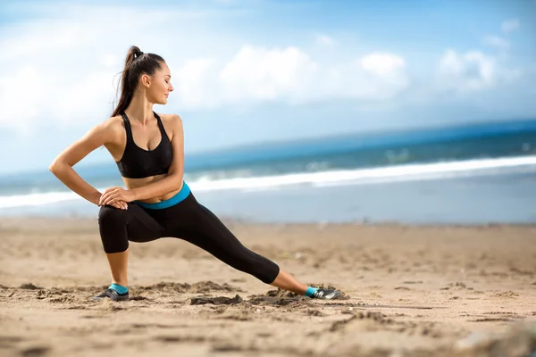 Atraktivní fit žena táhnoucí se na pláži — Stock fotografie