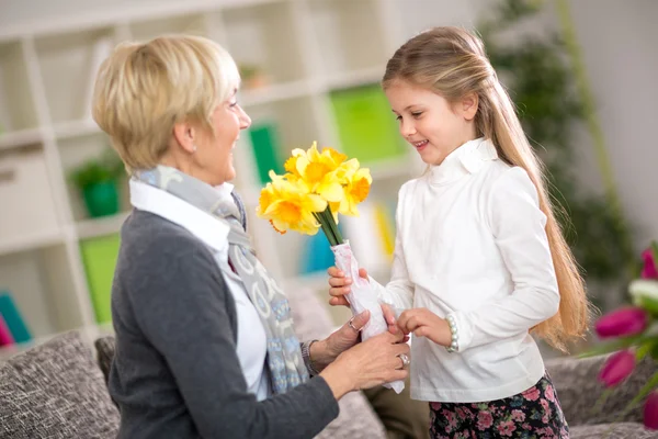 Nieta trayendo flores amarillas a su abuela — Foto de Stock