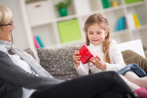 Söt flicka öppnar present presenteras av mormor — Stockfoto