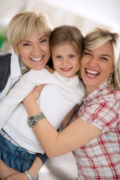 Smiling grandmother and mother embracing little girl — Stock Photo, Image