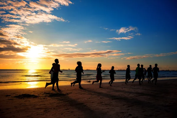 Люди бегают по пляжу красивым летом — стоковое фото