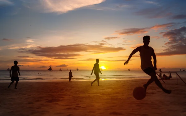 Sunset silhouettes playing beach football — Stock Photo, Image