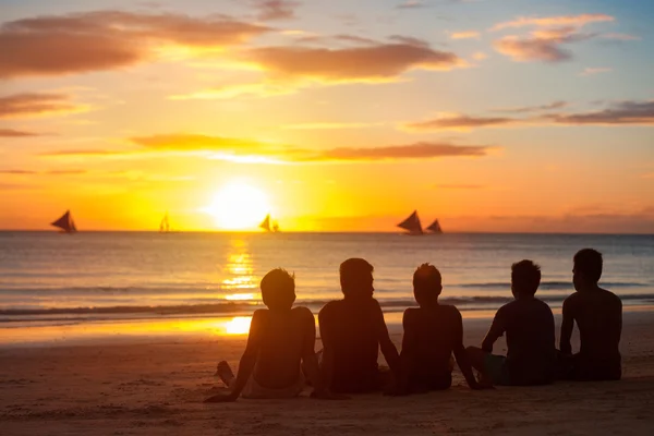 Группа молодых людей, друзей, команда, сидящая вместе на пляже — стоковое фото