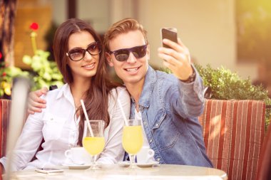 happy couple taking selfie in a cafe clipart