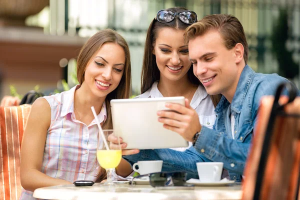 Mladí lidé při pohledu na počítači tablet pc v kavárně mimo — Stock fotografie