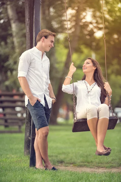 Par i park flicka på swing — Stockfoto