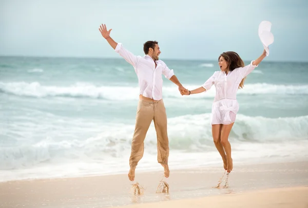 Pareja feliz saltando en la playa — Foto de Stock