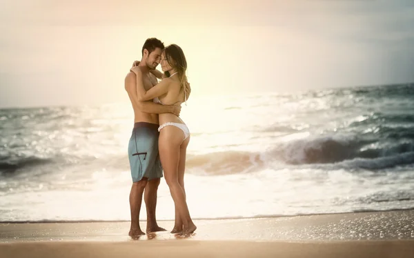 Молодая красивая пара влюблена на пляже на закате — стоковое фото