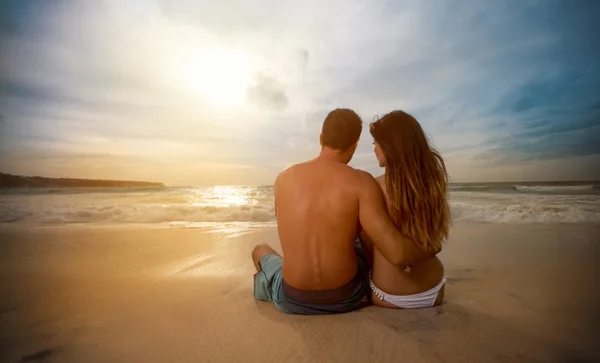 Paar op zoek zonsondergang op het strand — Stockfoto