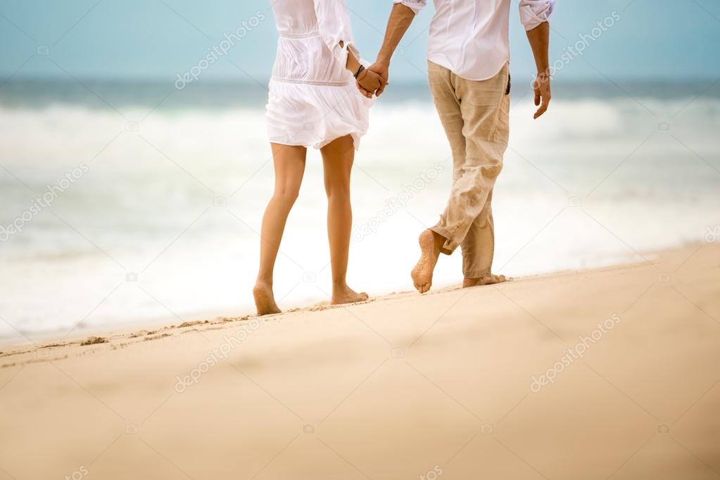 Barefoot couple walking on beach Stock Photo by ©luckybusiness 80366508
